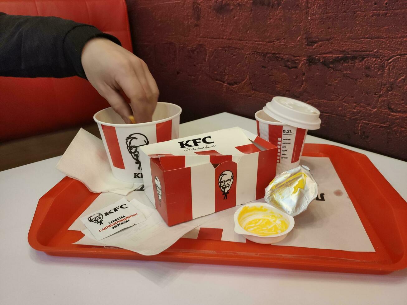 Stavropol, Rússia - abril 2023 kfc velozes Comida restaurante. homem levando Fora francês fritas a partir de uma caixa foto