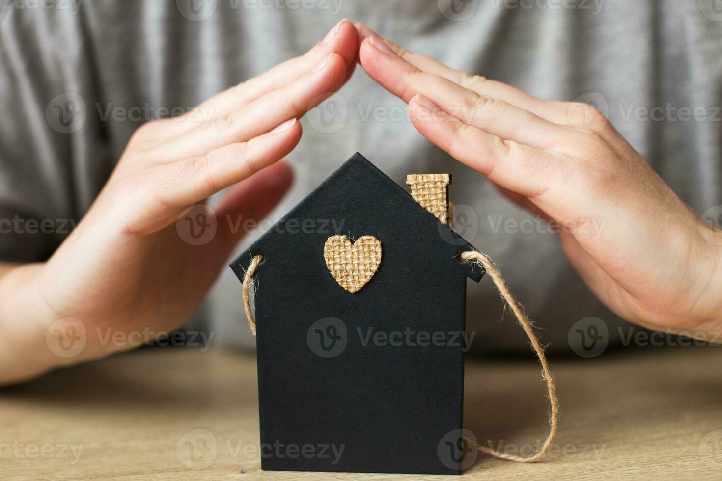 casinha de brinquedo coberta de mão da mulher. conceito de seguro residencial foto
