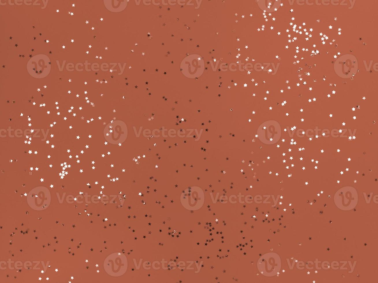 Estrelas de confete cintilando em um fundo laranja foto