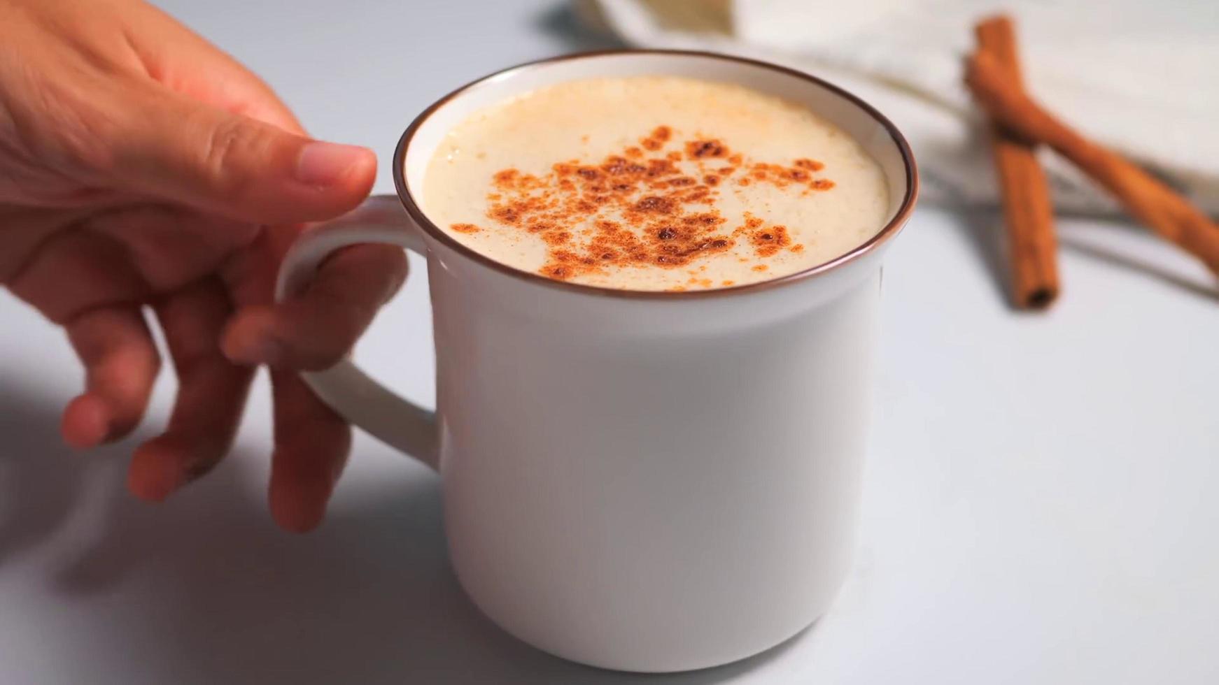 mão segurando uma xícara branca de café com leite ou café em fundo branco foto