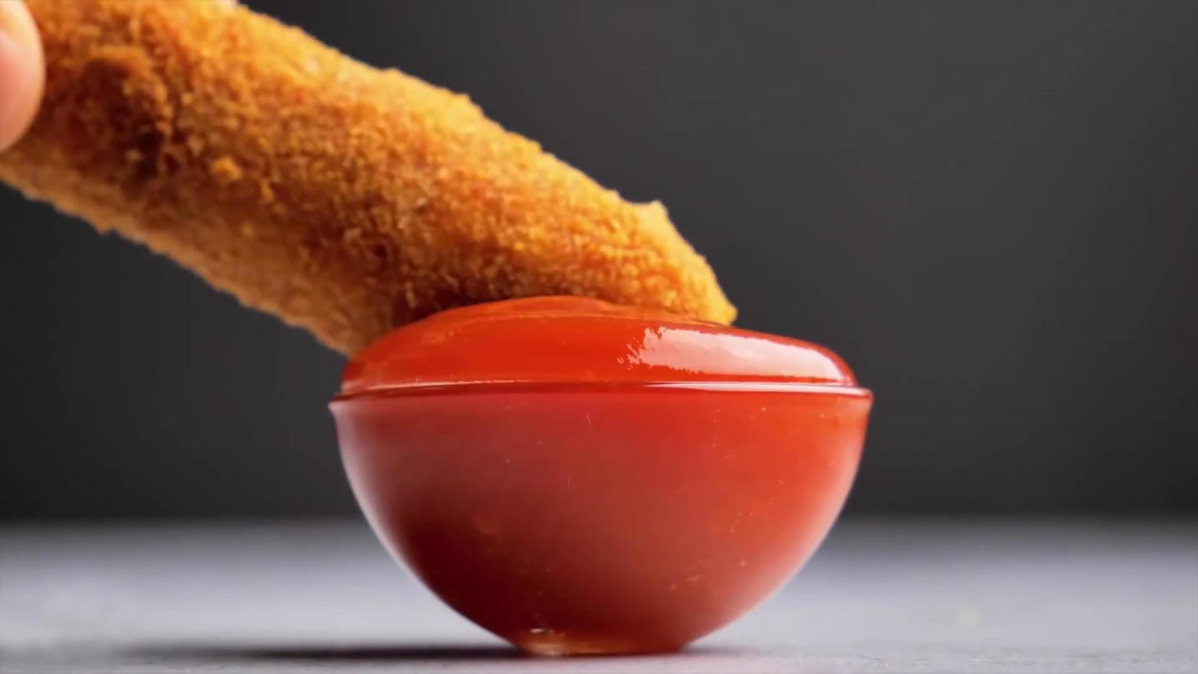 uma batata frita mergulhada em uma tigela de vidro cheia de ketchup foto
