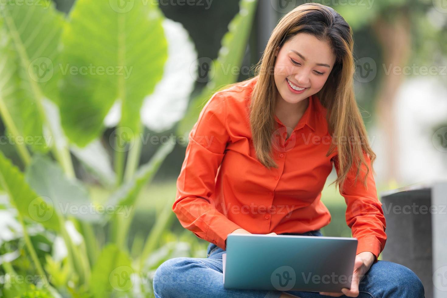 bela jovem usando laptop sentada no parque da cafeteria foto