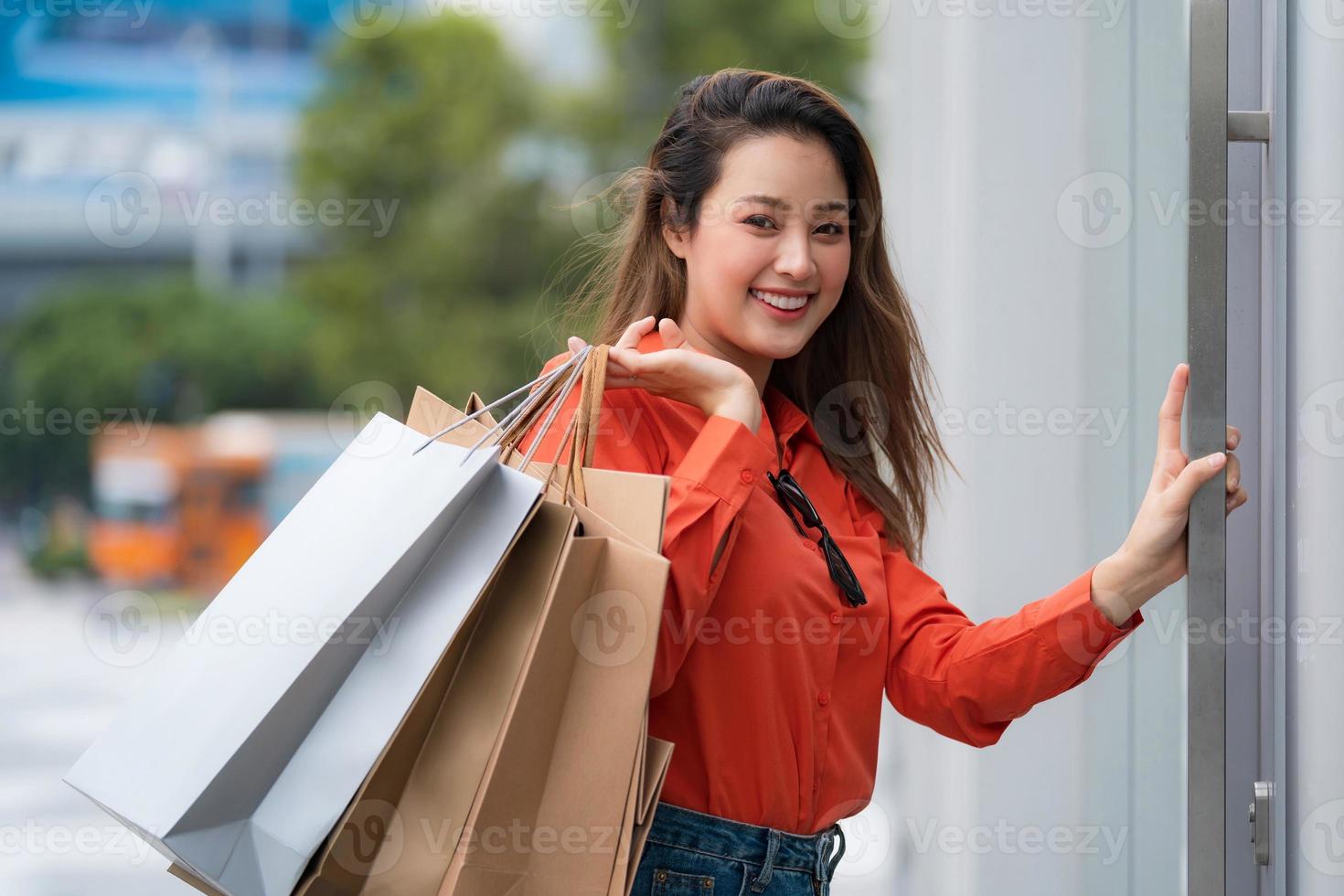 retrato ao ar livre de uma mulher feliz segurando sacolas de compras foto