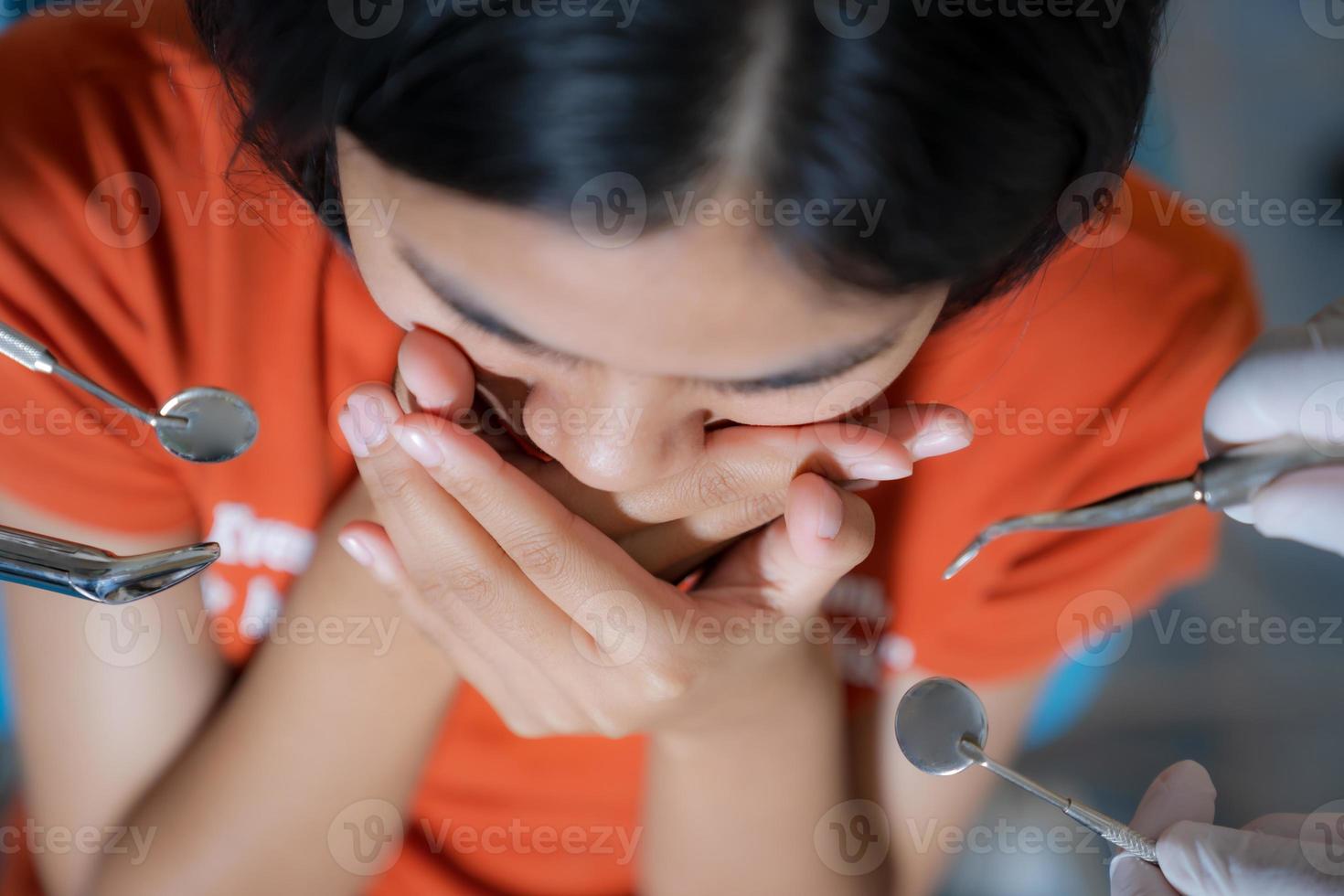 menina assustada com dentistas cobre a boca no consultório do dentista foto