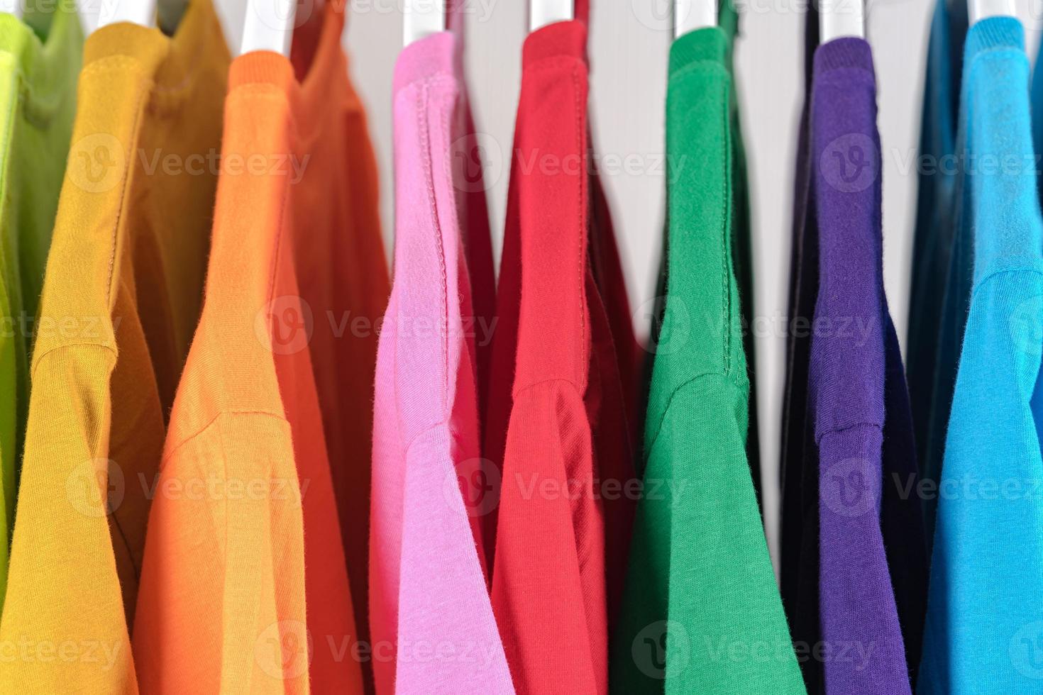 close-up de camisetas de roupas em cabides no fundo branco foto