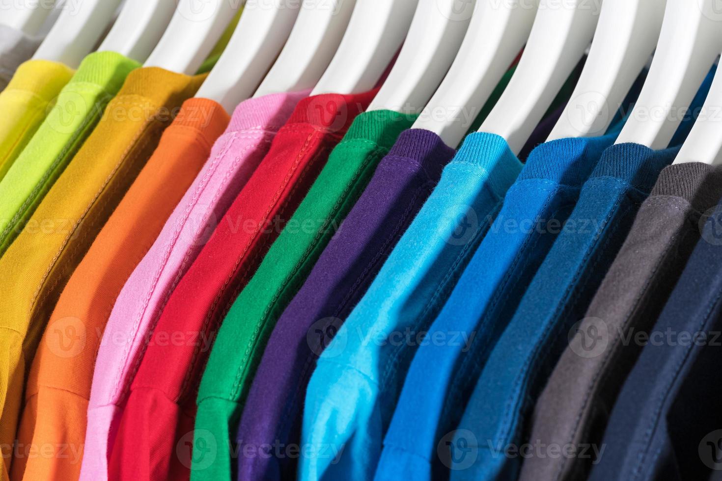 close-up de camisetas de roupas em cabides no fundo branco foto