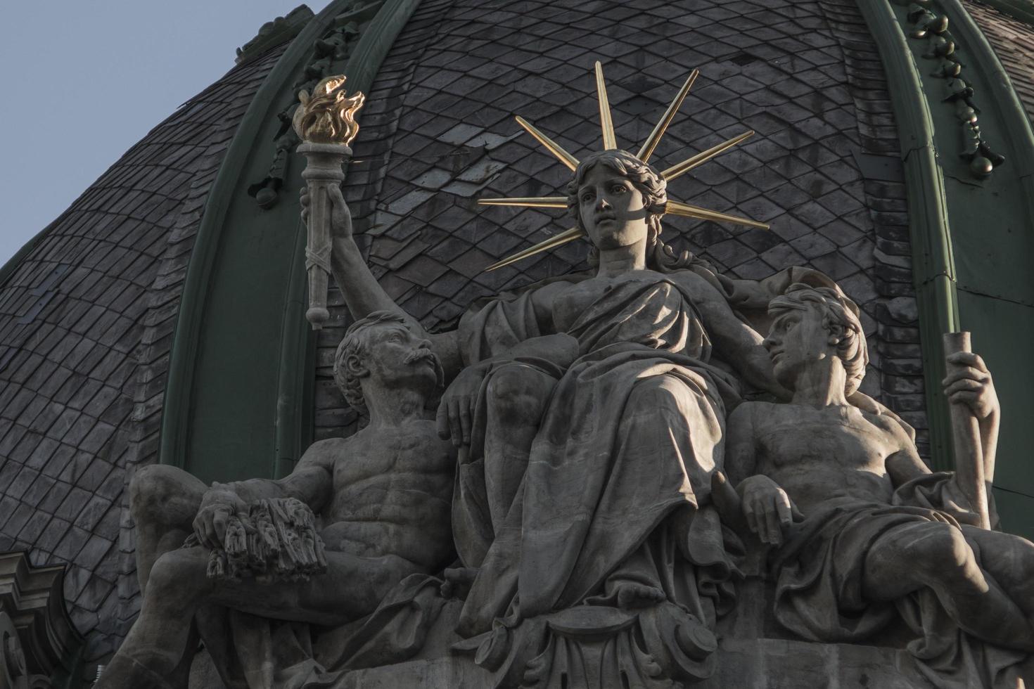 uma estátua da liberdade está sentada com uma tocha na mão e dois companheiros foto