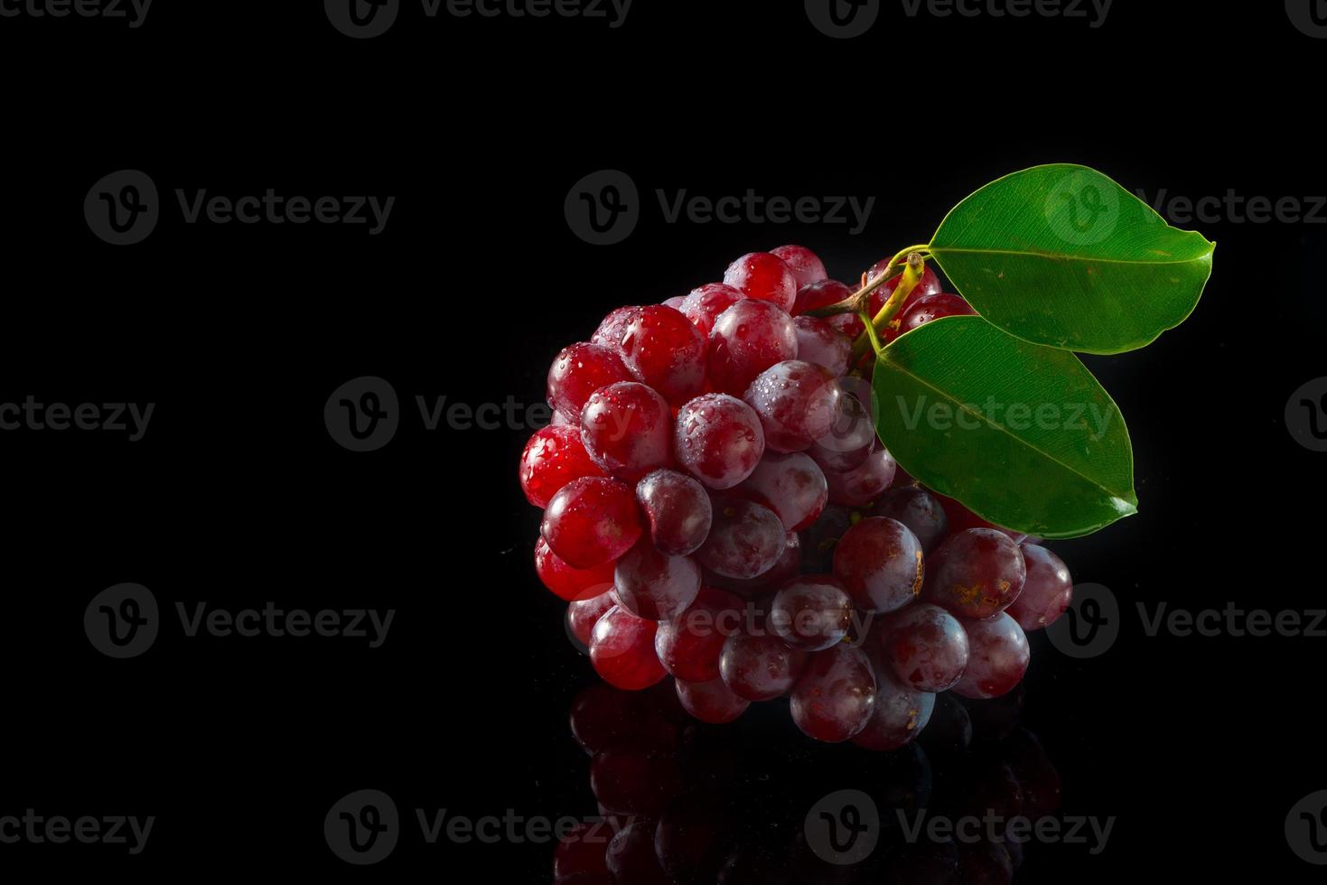 uvas vermelhas em acrílico preto foto