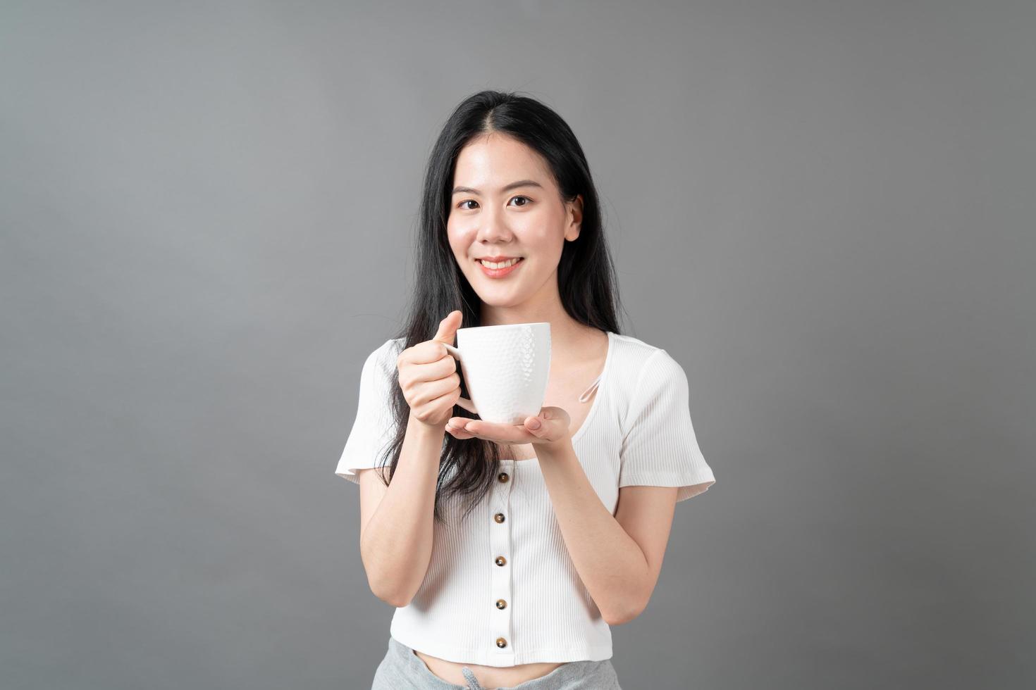 jovem mulher asiática com um rosto feliz e uma mão segurando uma xícara de café foto