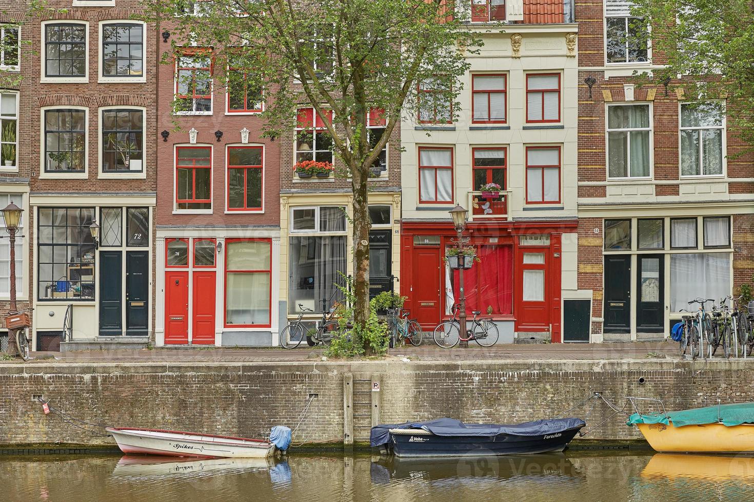 canal de amsterdã com casas e casas flutuantes holandesas típicas foto