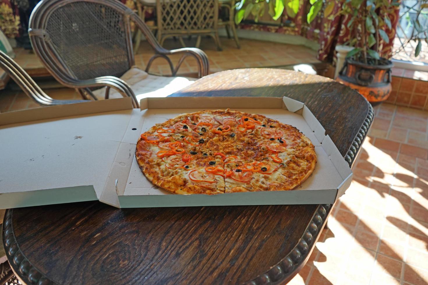 pizza grande em uma caixa de papelão sobre uma mesa de madeira foto