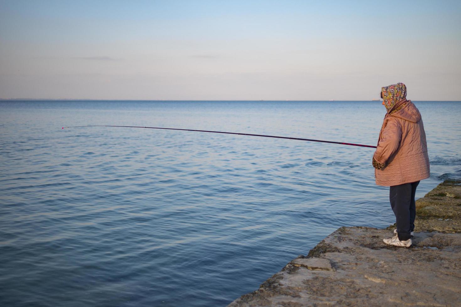 pescador idoso no cais pega peixe foto