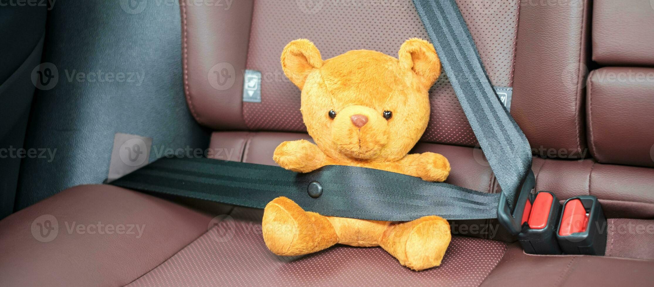 amarelo Urso boneca fixação assento cinto durante sentado dentro uma carro e dirigindo em a estrada. carro assento, segurança, viagem, viagem e transporte conceito foto