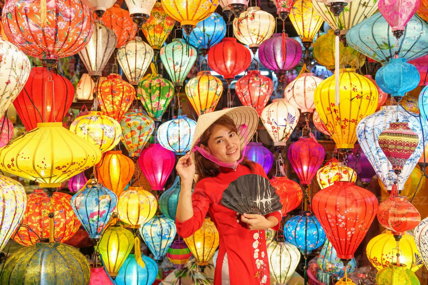 feliz mulher vestindo ao dai vietnamita vestir com colorida lanternas, viajante passeios turísticos às Hoi a antigo Cidade dentro central vietnam.landmark para turista atrações.vietnam e sudeste viagem conceito foto