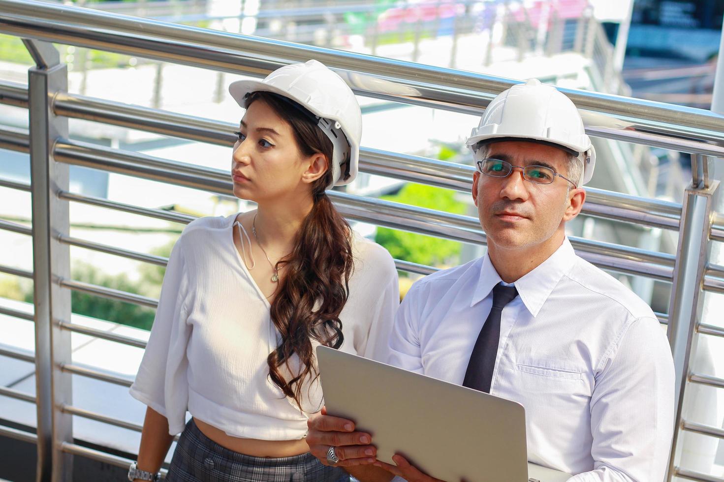 engenheiros inspecionam o local projetos de construção ao ar livre no moderno centro da cidade. engenheiros usam capacetes de segurança brancos para segurança foto