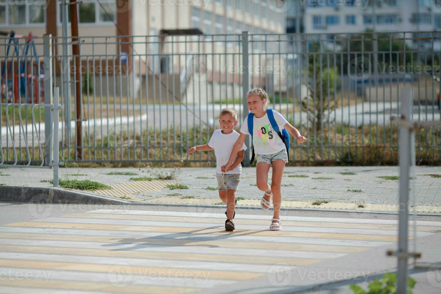 irmão e irmã corre através uma pedestre cruzando. crianças corre ao longo a estrada para Jardim da infância e escola.zebra tráfego andar caminho dentro a cidade. conceito pedestres passagem uma faixa de pedestre foto