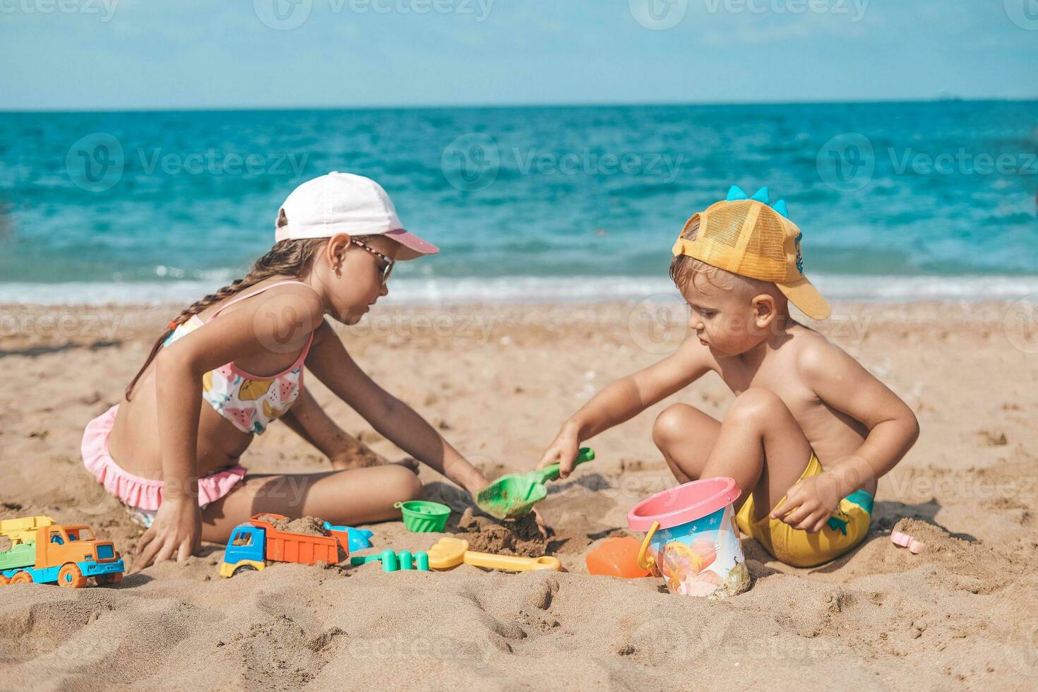 crianças estão jogando em a de praia. verão água Diversão para a todo família. uma Garoto e uma menina estão jogando com areia em a Beira Mar. foto