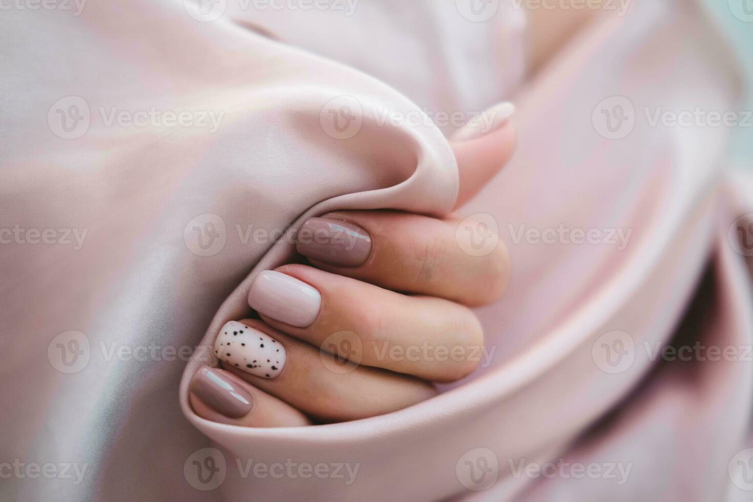 mulheres - mão com lindo manicure aguarde uma seda tecido. outono tendência, polonês a bege e Codorna padronizar em a unhas com gel polonês, shellac. cópia de espaço. foto