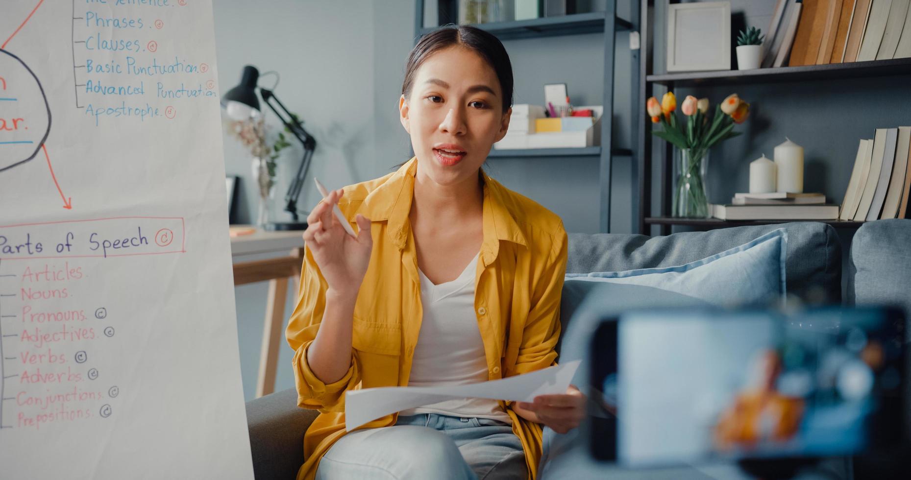 jovem asiática professora de inglês videoconferência ligando no smartphone conversa por webcam aprender ensinar no bate-papo online em casa foto