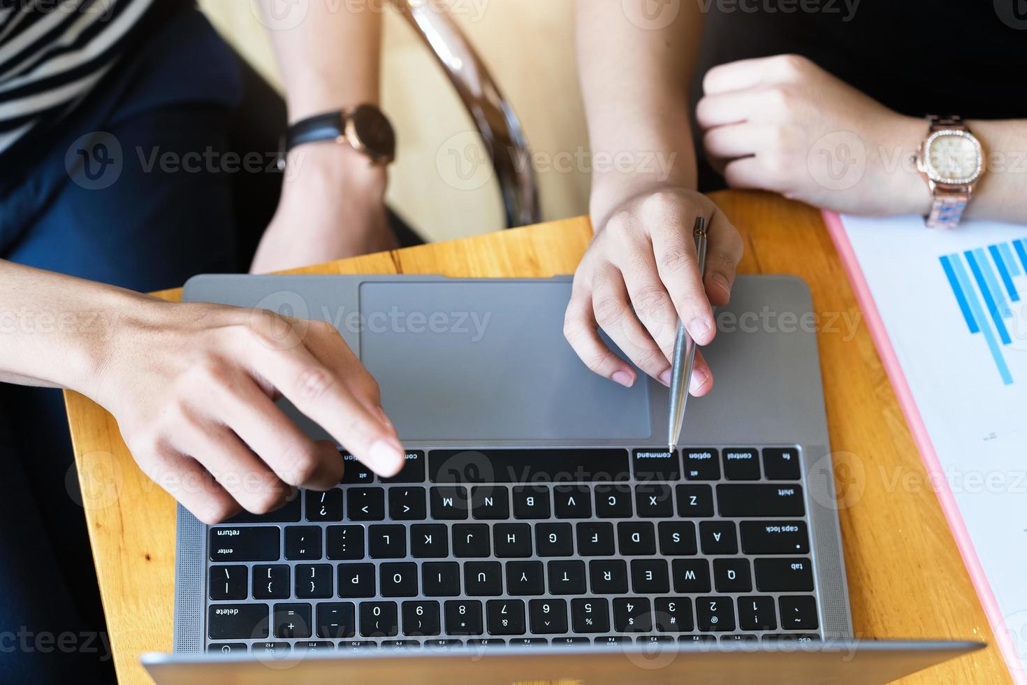 concentre-se na mão segurando uma caneta que aponta para a tela do laptop foto