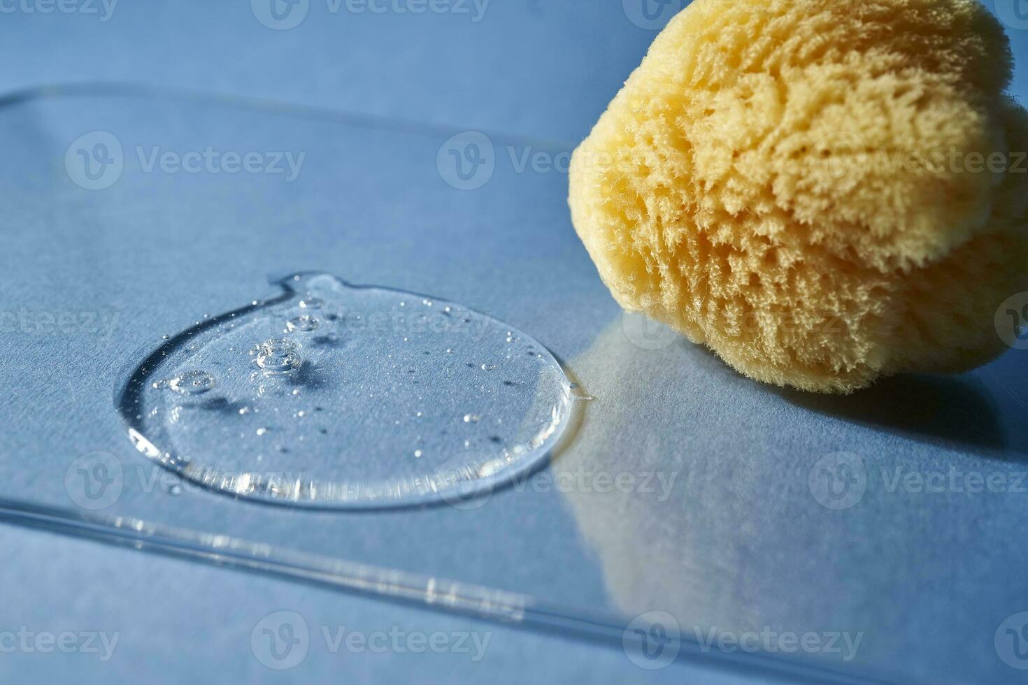 uma natural esponja e uma solta do gel ou xampu em uma azul fundo. foto