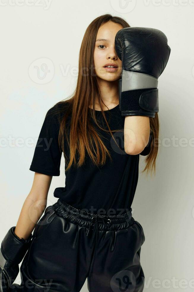 lindo menina dentro Preto Esportes uniforme boxe luvas posando ginástica Treinamento foto