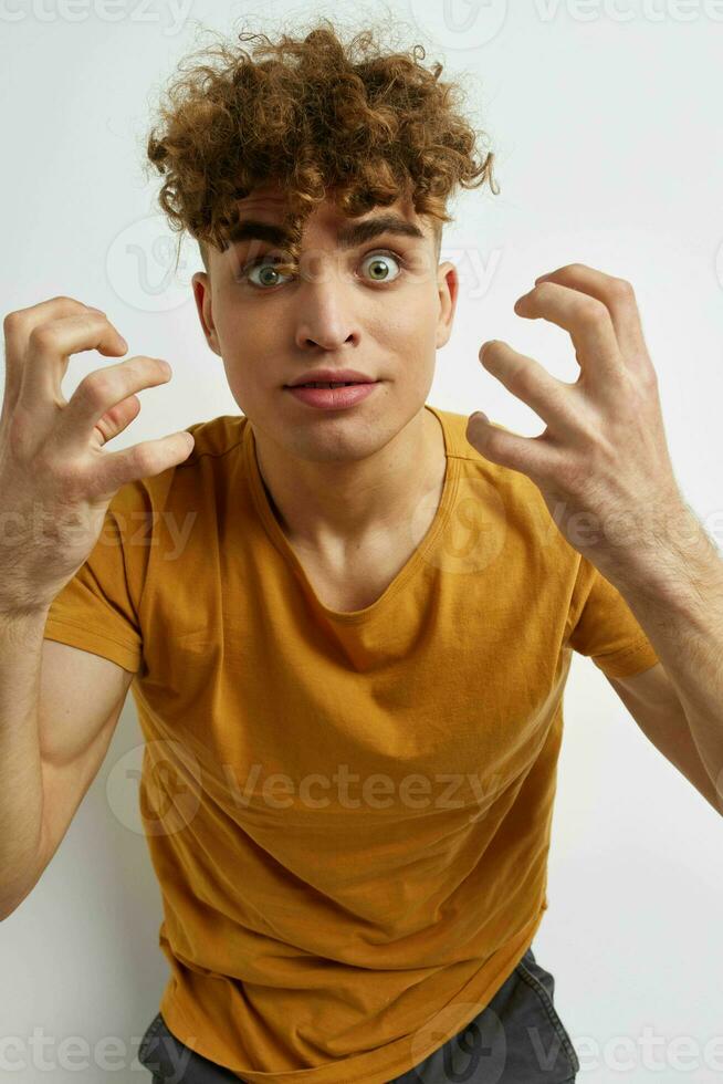 atraente homem dentro amarelo Camisetas gesto mãos emoções luz fundo foto