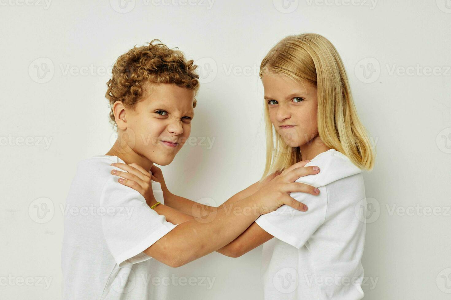 retrato do fofa crianças dentro branco Camisetas estão em pé Próximo para bege fundo foto