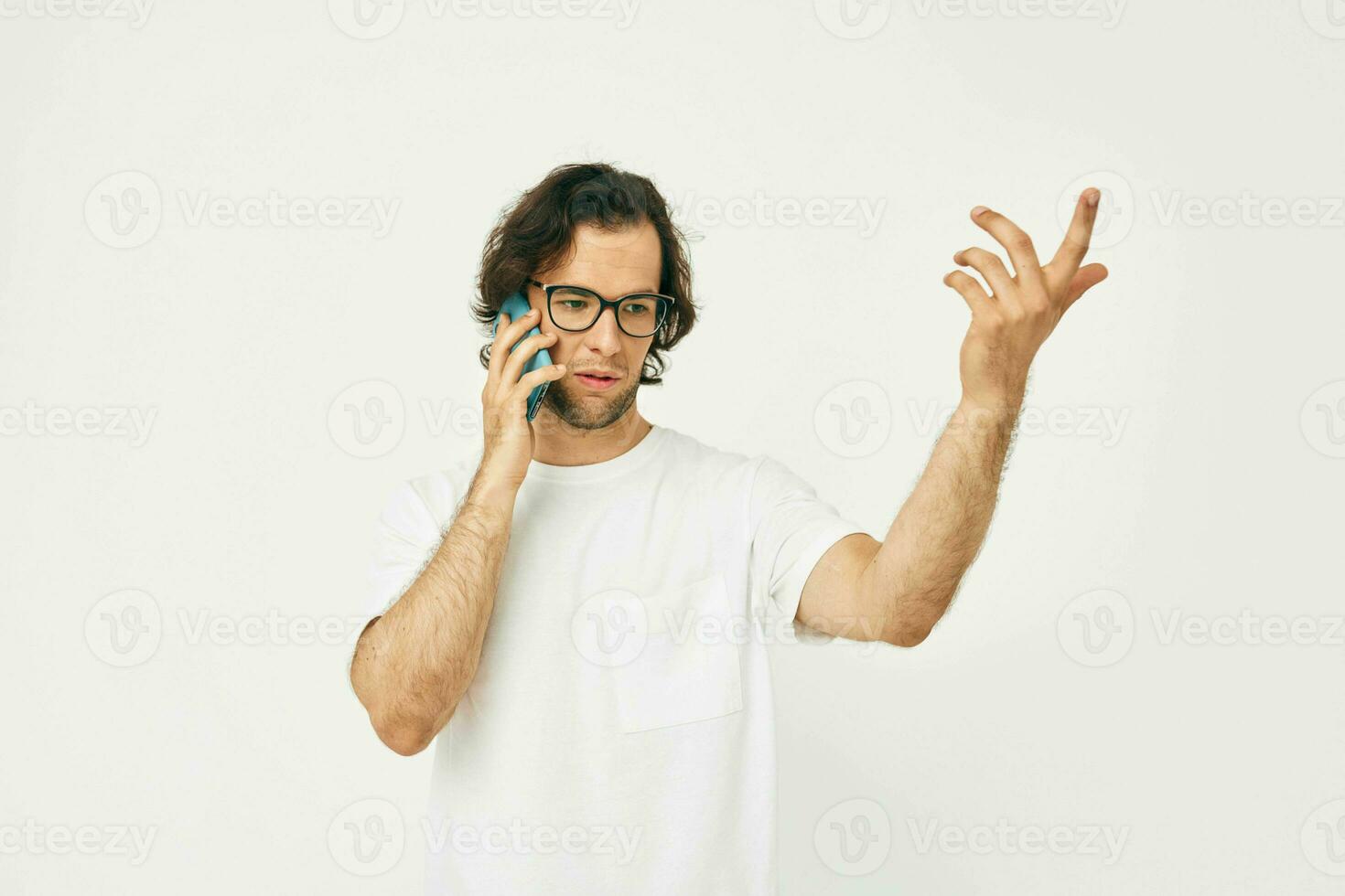 atraente homem dentro uma branco camiseta comunicação de telefone luz fundo foto