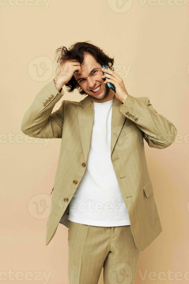 bonito homem comunicação de telefone bege terno elegante estilo isolado fundo foto