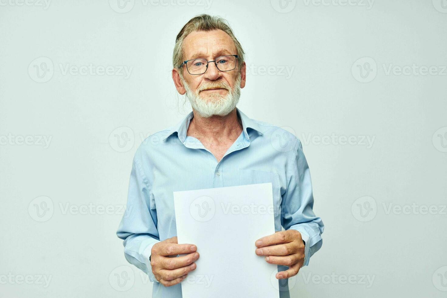 velho homem dentro uma azul camisa e óculos uma branco Folha do papel luz fundo foto