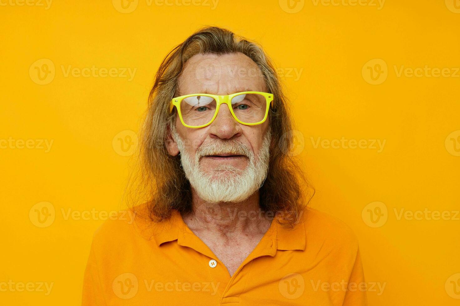 Senior grisalho homem amarelo camiseta e óculos posando amarelo fundo foto