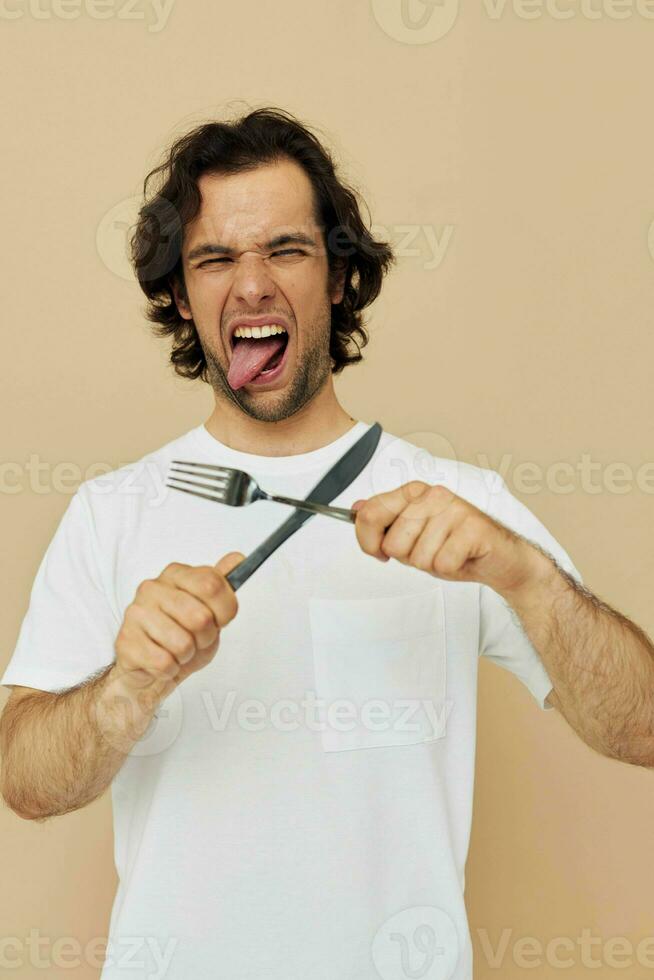 alegre homem emoções faca e garfo utensílios de cozinha isolado fundo foto