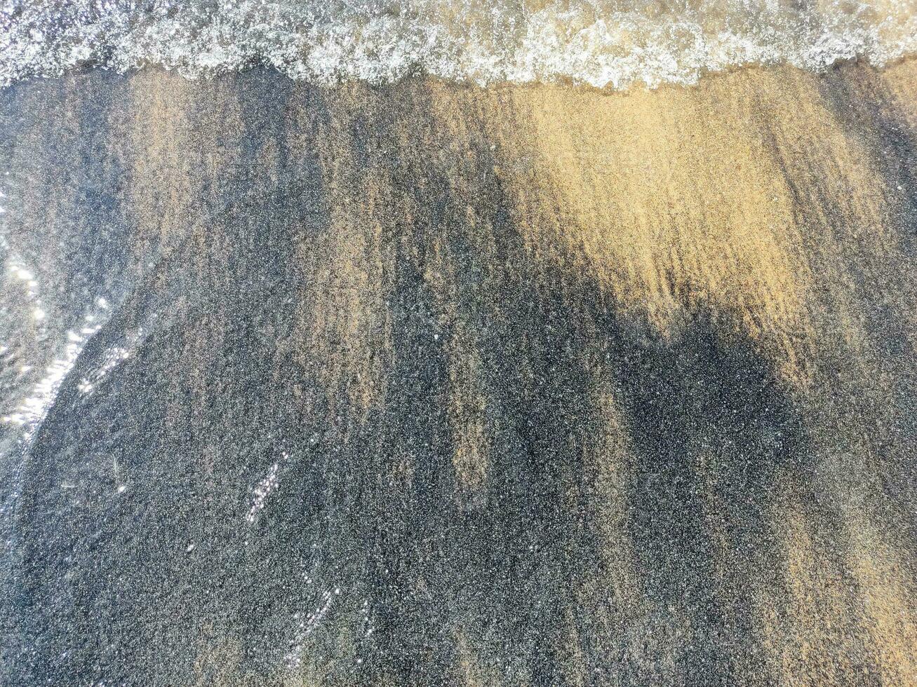 de praia molhado areia textura. arenoso costa bege fundo. foto