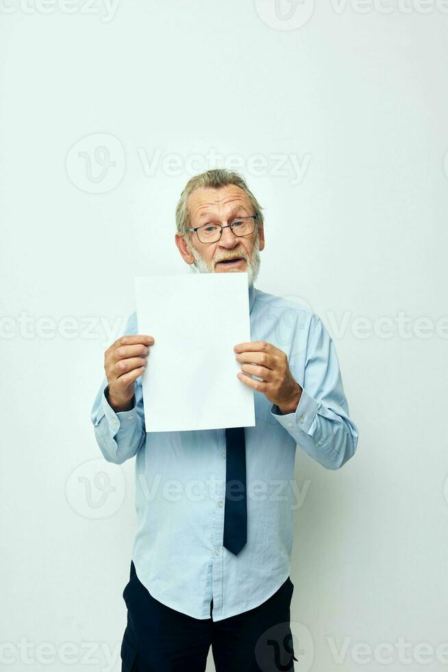 retrato do feliz Senior homem segurando documentos com uma Folha do papel luz fundo foto