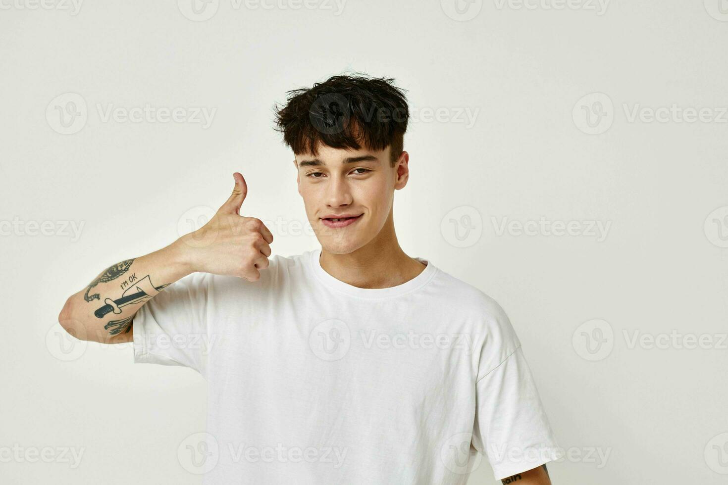 uma jovem homem moderno juventude estilo branco camiseta tatuagem em a braço estilo de vida inalterado foto