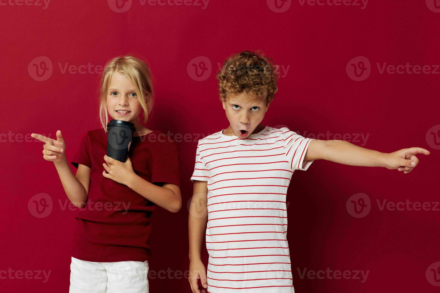 Garoto e menina descartável vidro com beber posando vermelho fundo foto