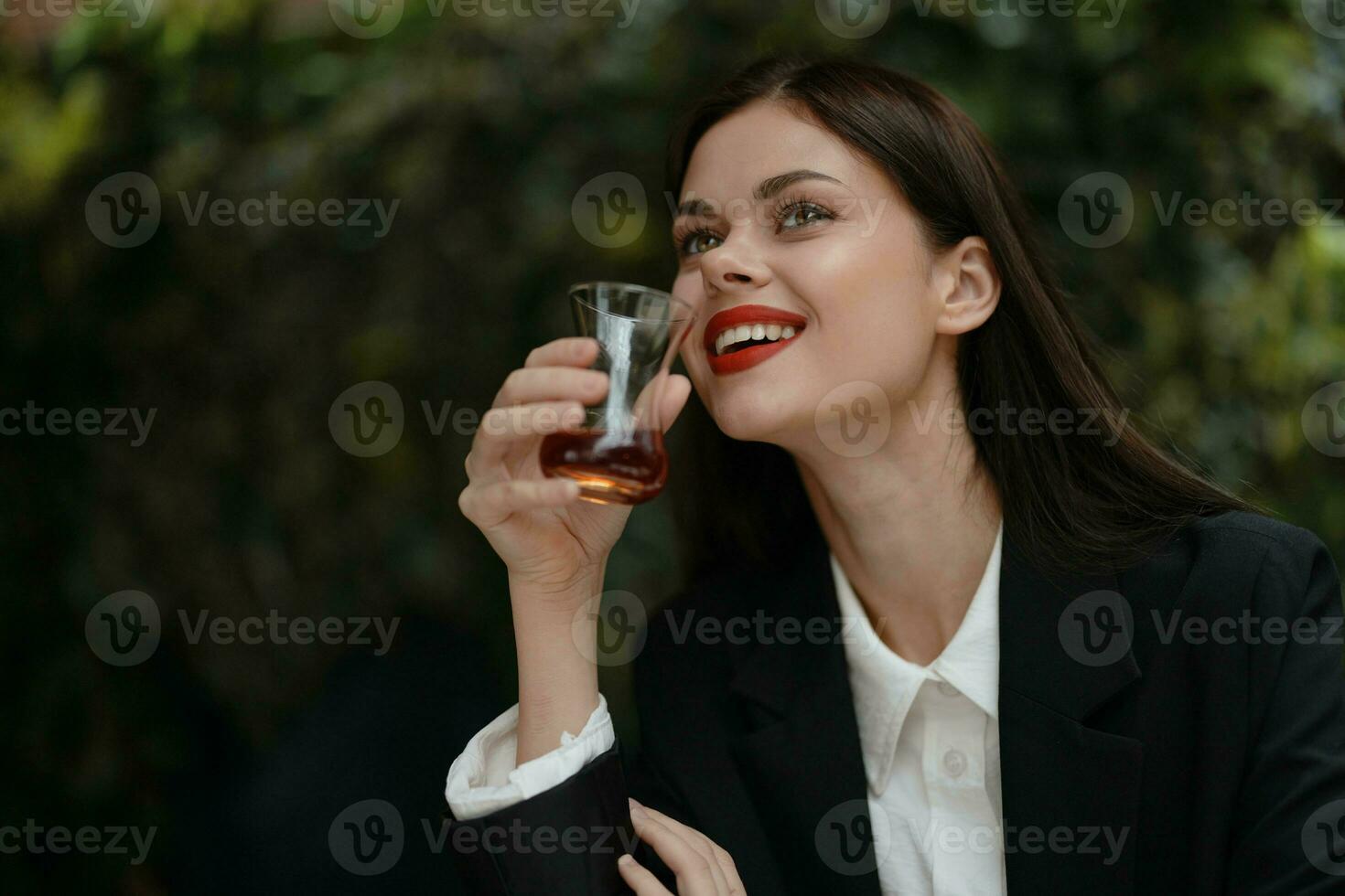 mulher sorrir com dentes bebendo chá dentro uma cafeteria a partir de uma turco vidro caneca em a rua, Primavera viagem, cidade pausa foto