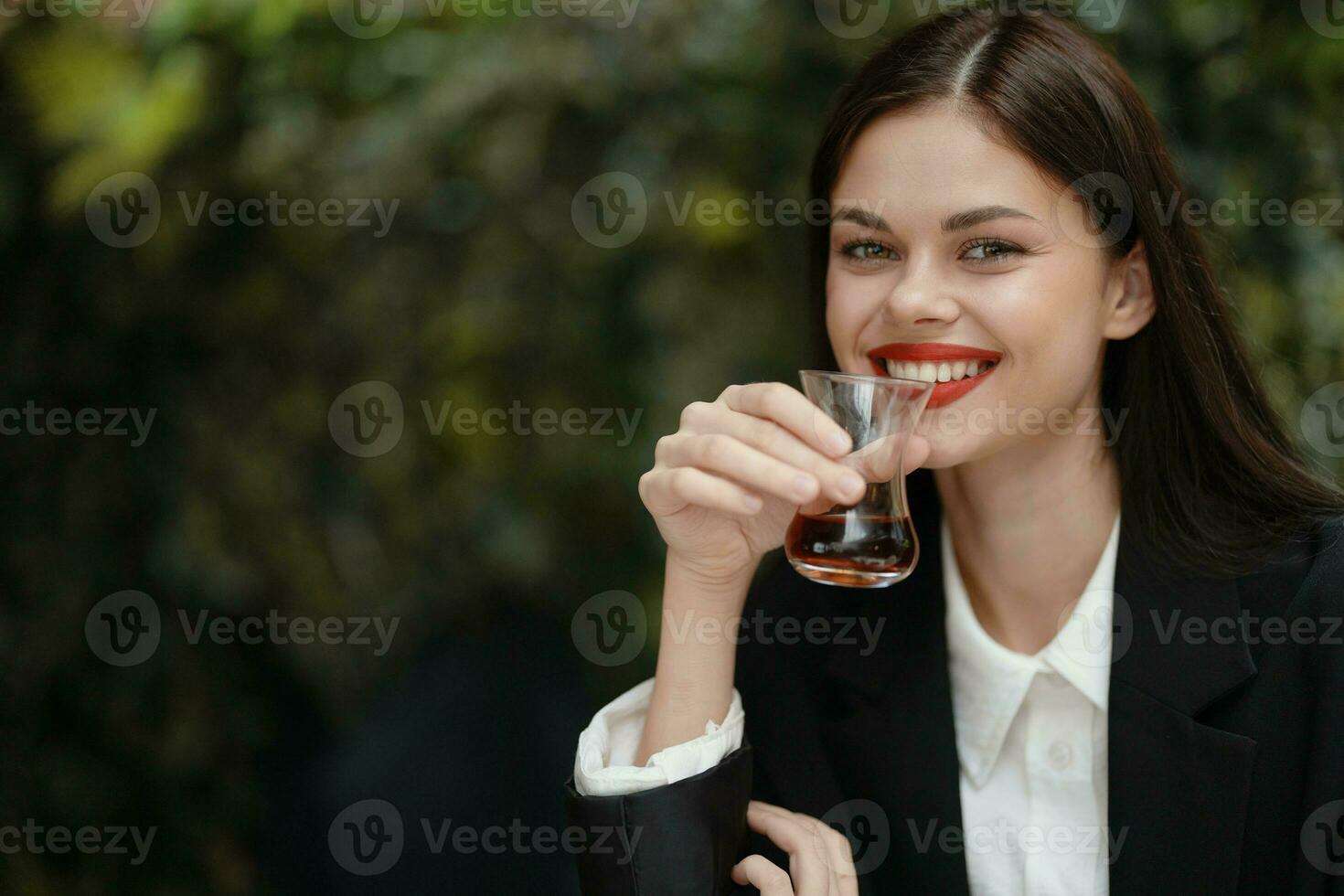 mulher sorrir com dentes bebendo chá dentro uma cafeteria a partir de uma turco vidro caneca em a rua foto