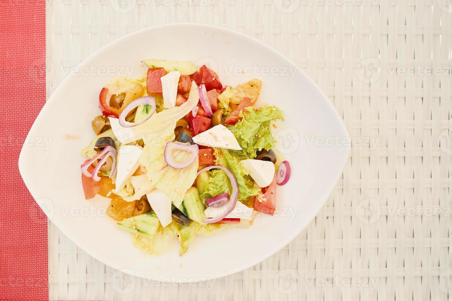 Salada vegetariana em prato de cerâmica na mesa de ráfia branca foto