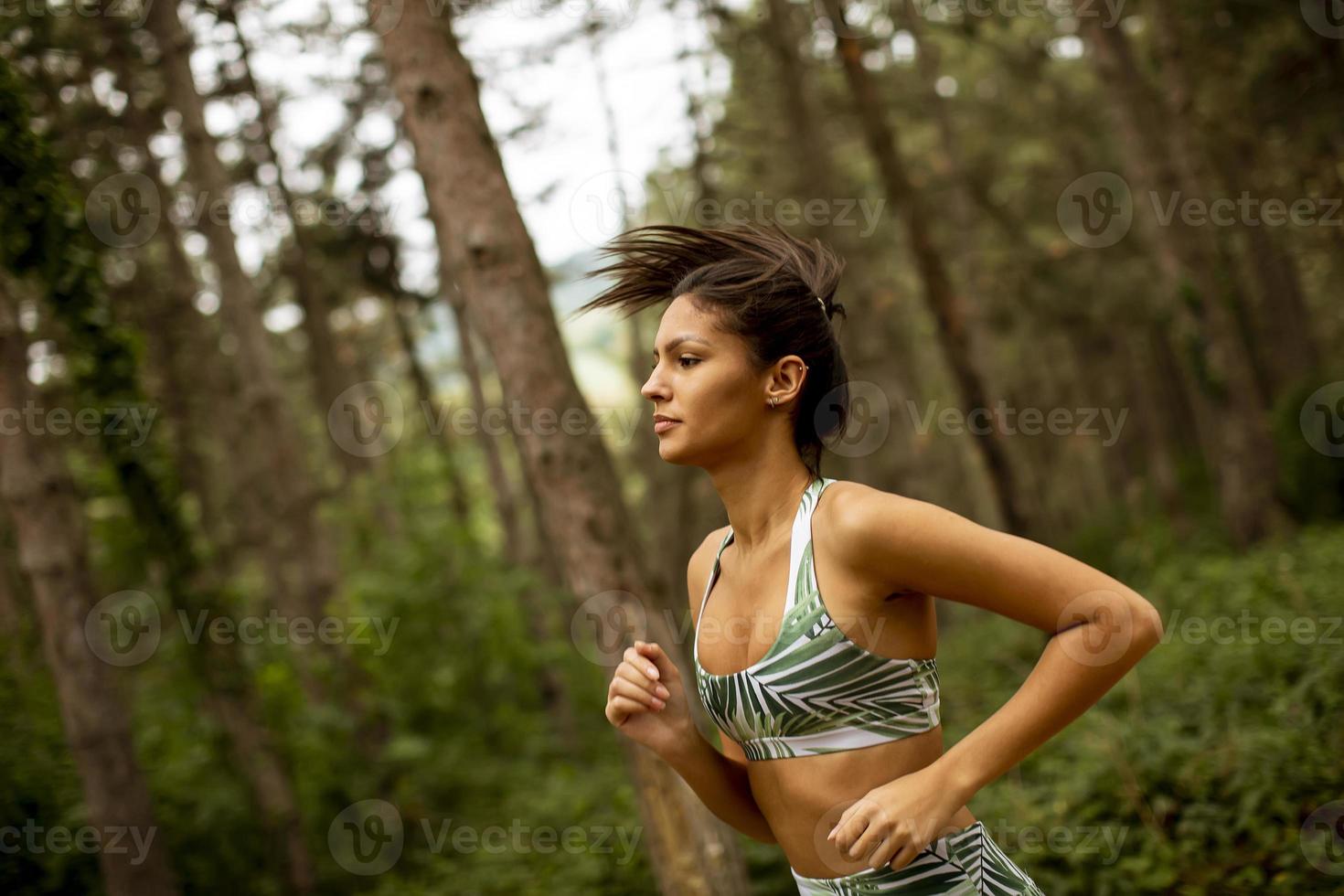 mulher jovem fitness correndo na trilha da floresta foto