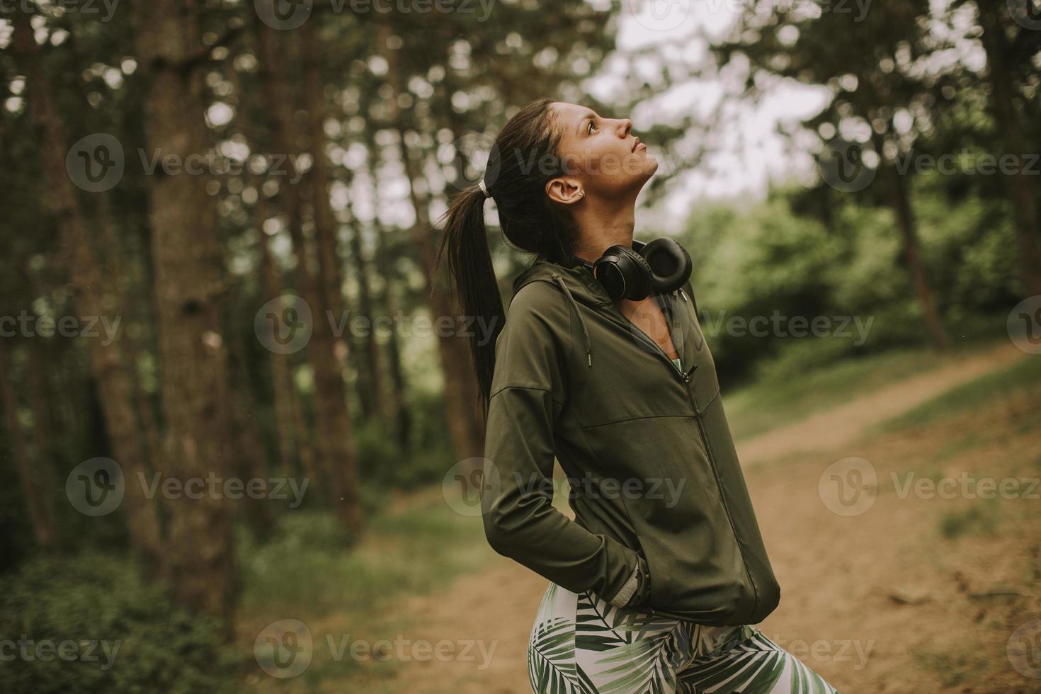 bela jovem corredora ouvindo música e fazendo uma pausa após correr em uma floresta foto