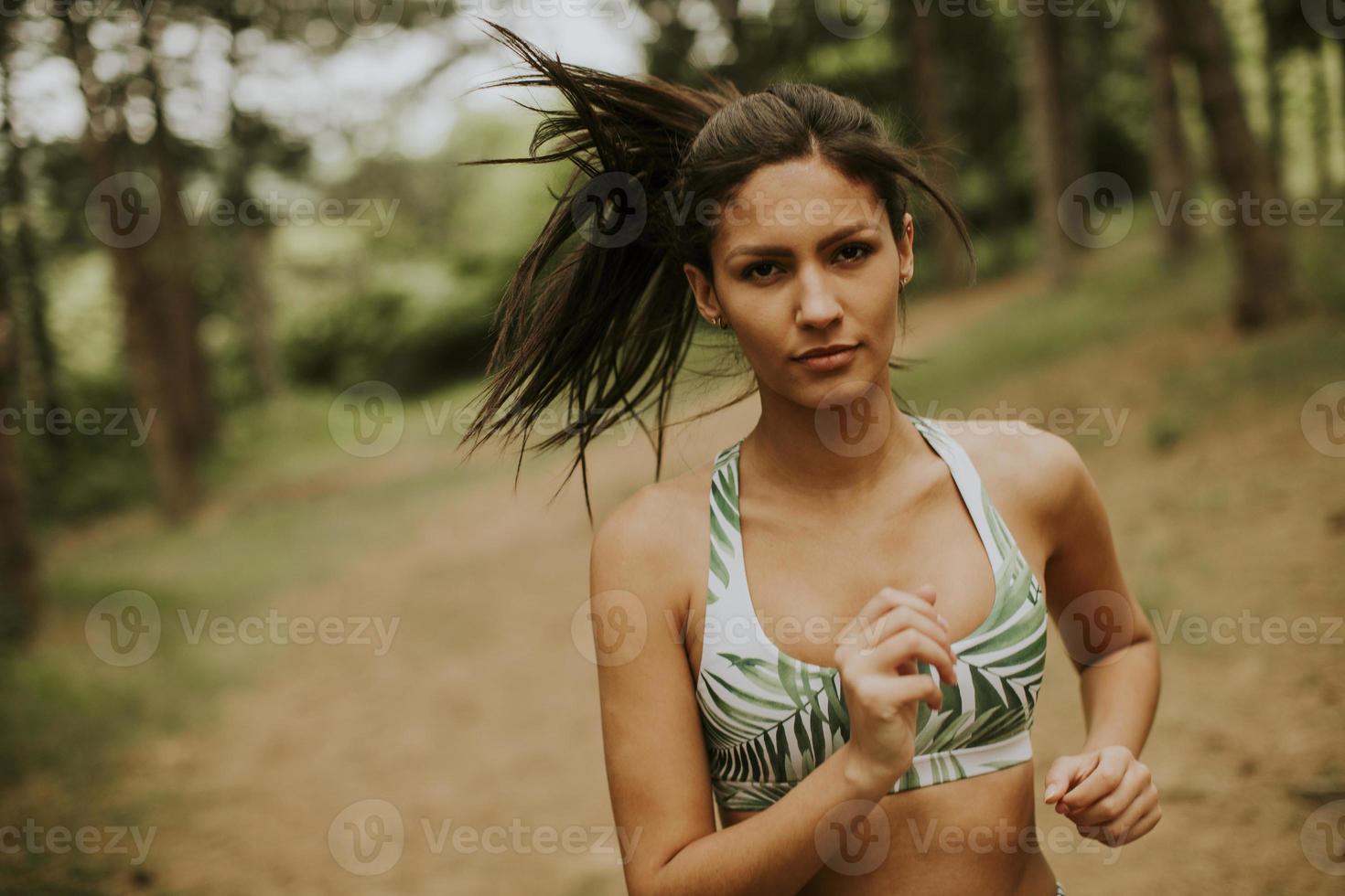 mulher jovem fitness correndo na trilha da floresta foto