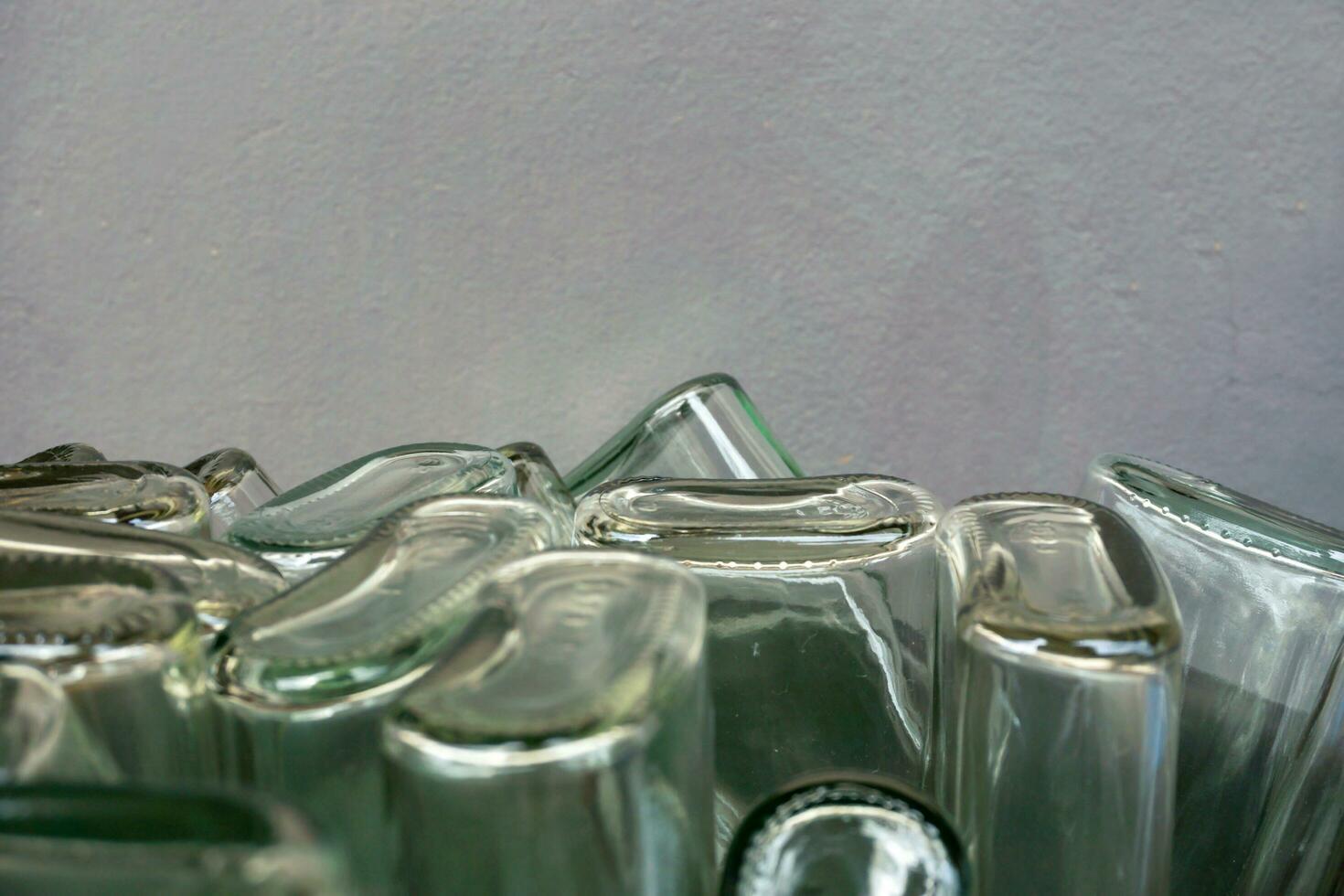 fechar-se e colheita do acima lado baixa e inferior do plano vidro garrafa em borrado cinzento fundo. foto