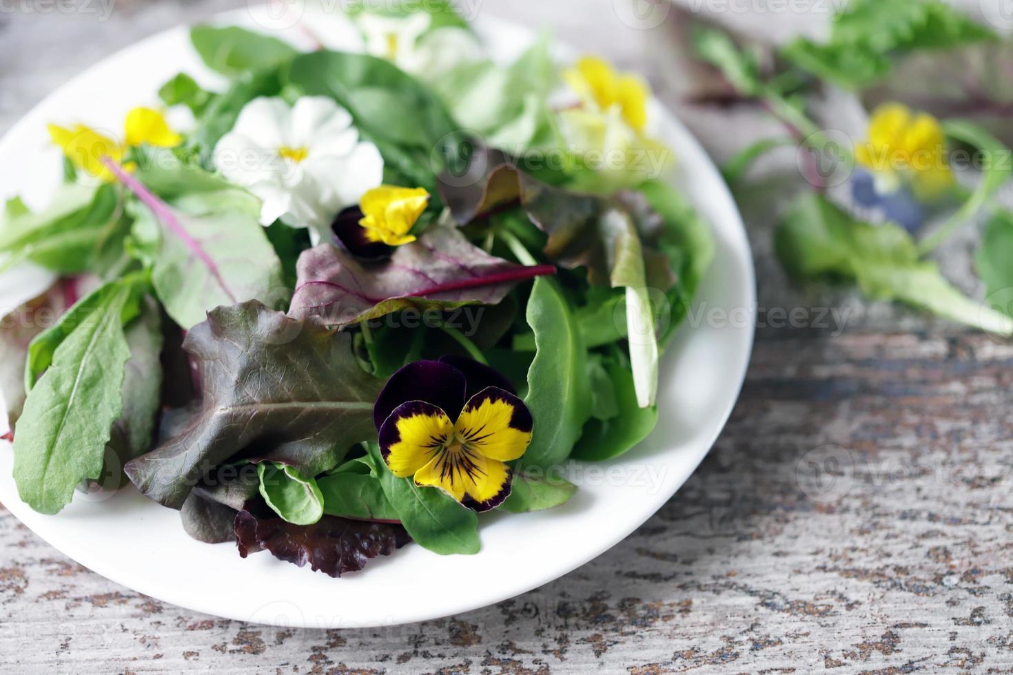 mix de salada com flores em um prato branco foto