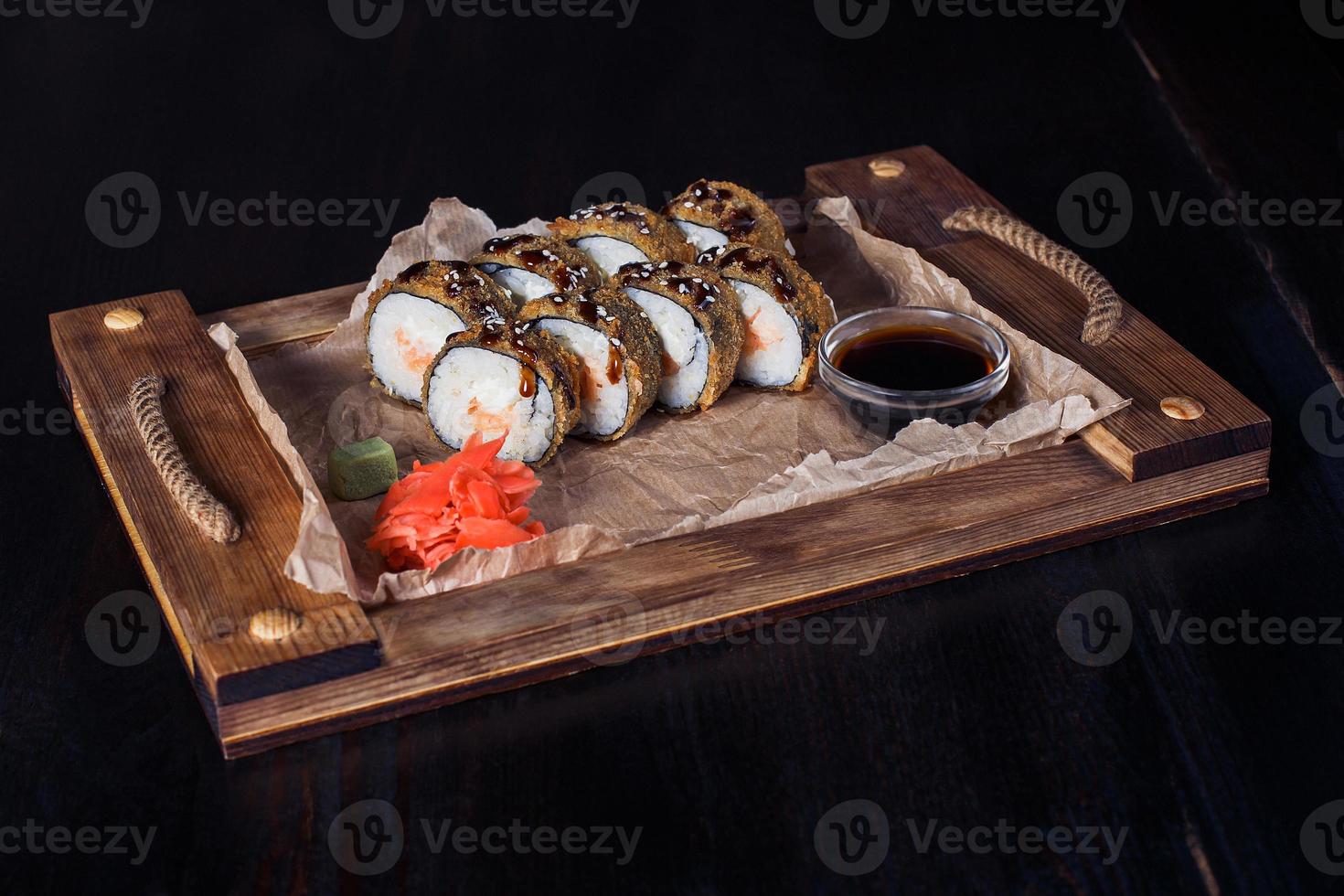 Rolinhos de frutos do mar em uma bandeja de madeira, bela porção, fundo escuro foto
