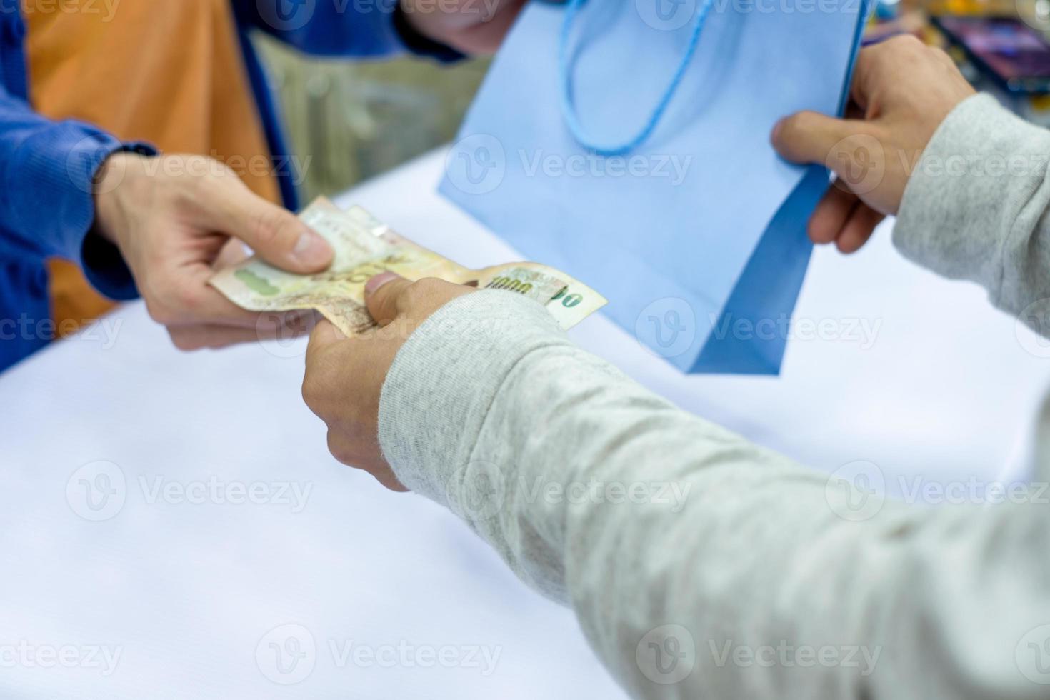 mão dando dinheiro e pegue a sacola de papel do caixa da equipe na loja foto