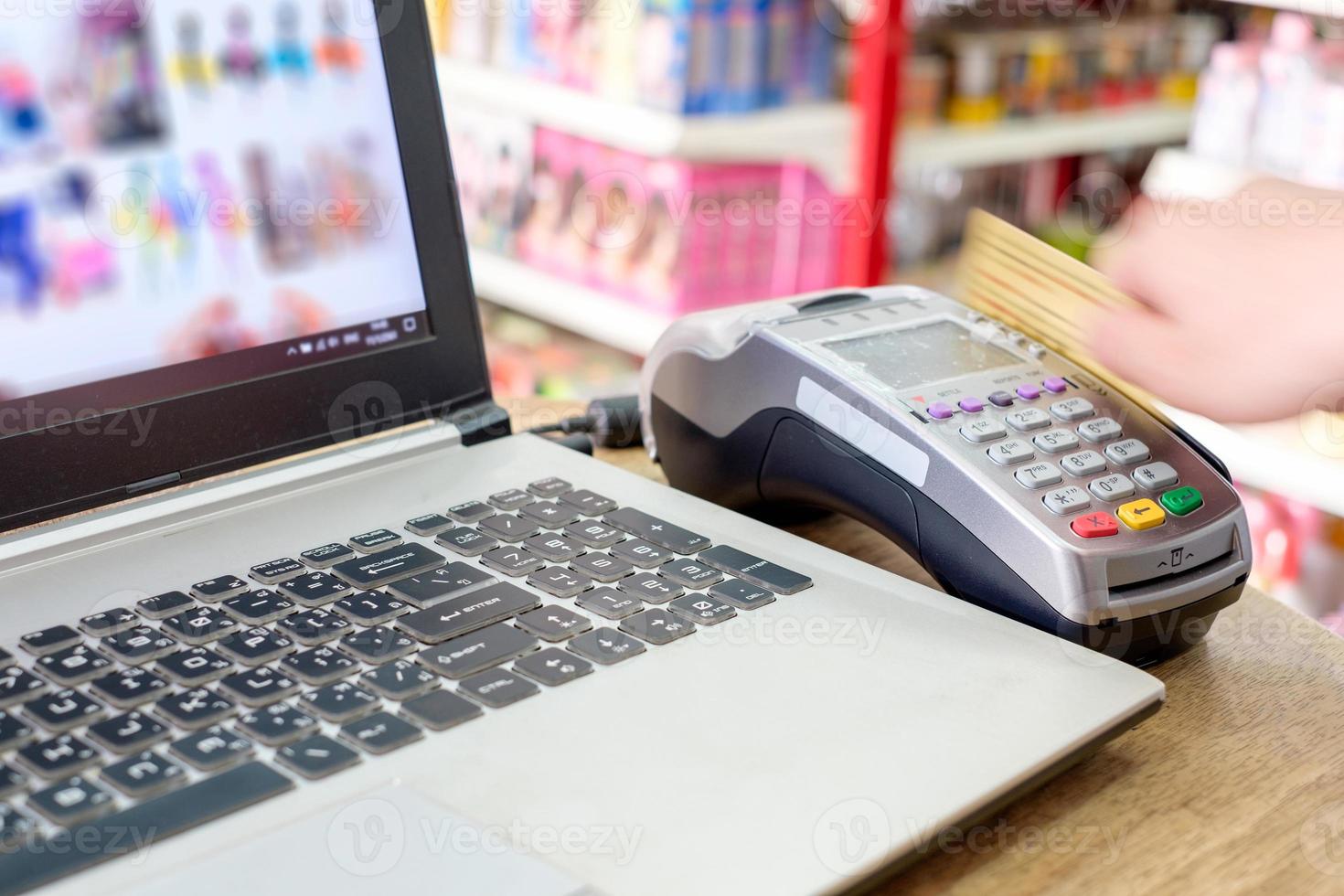 passando a mão com o cartão de crédito no ternimal e usando o laptop para fazer compras online foto