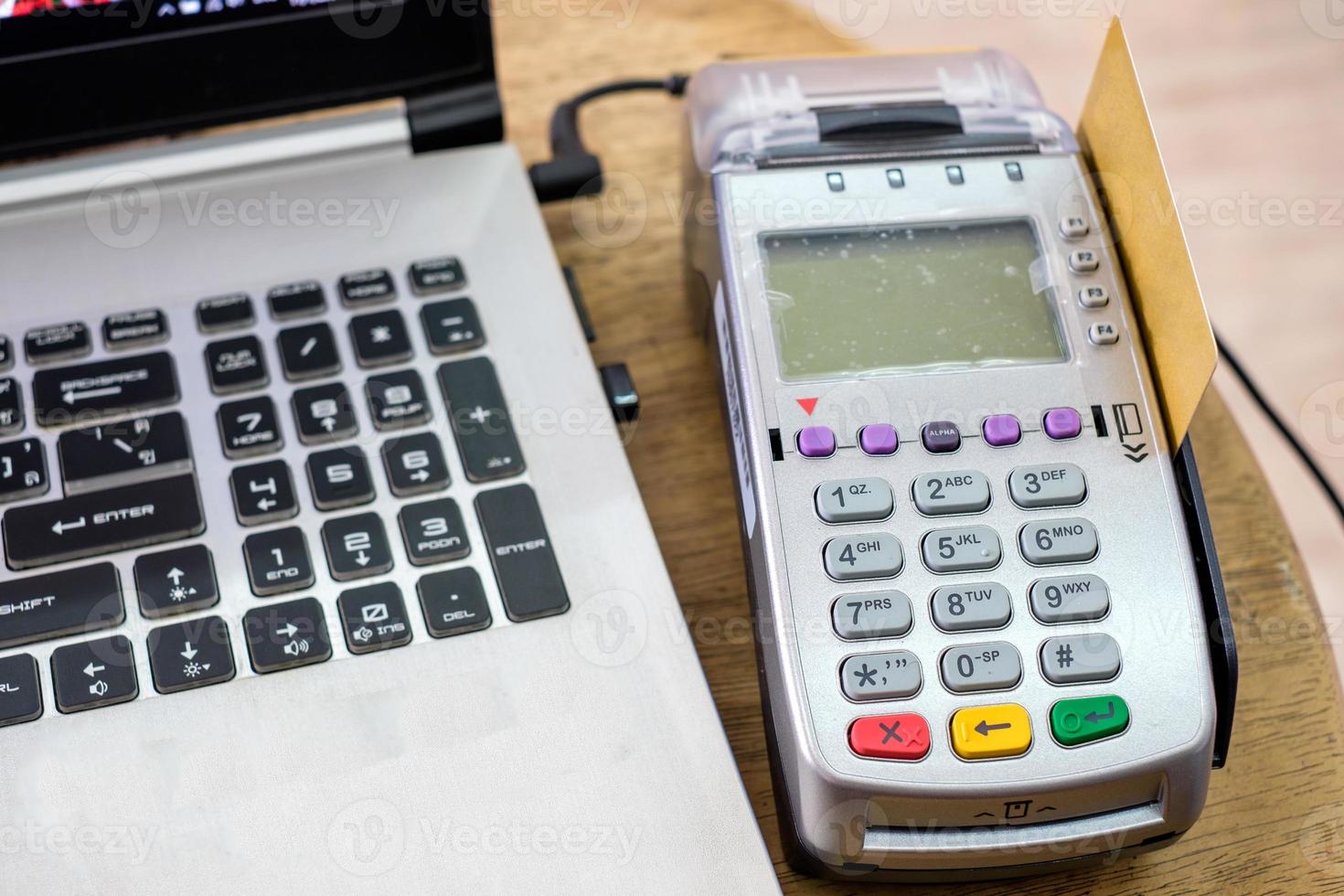 usando cartão de crédito no terminal de pagamento com o laptop na mesa foto