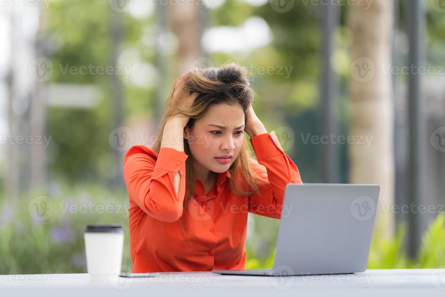 Mulher jovem e bonita com rosto feliz e surpreso usando laptop em um parque da cidade foto